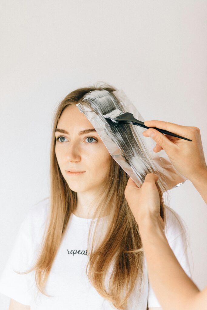 A woman is coloring her hair using color treatment