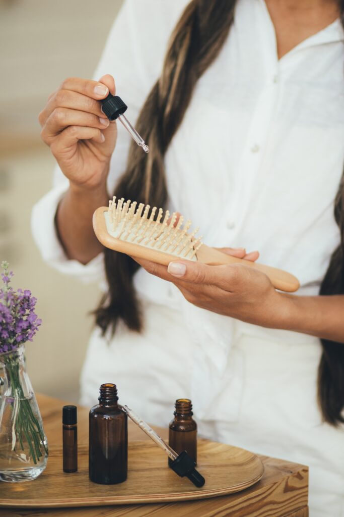 Young woman applying natural organic essential oil on hair and skin. Home spa and beauty rituals. Skin care. hair treatments