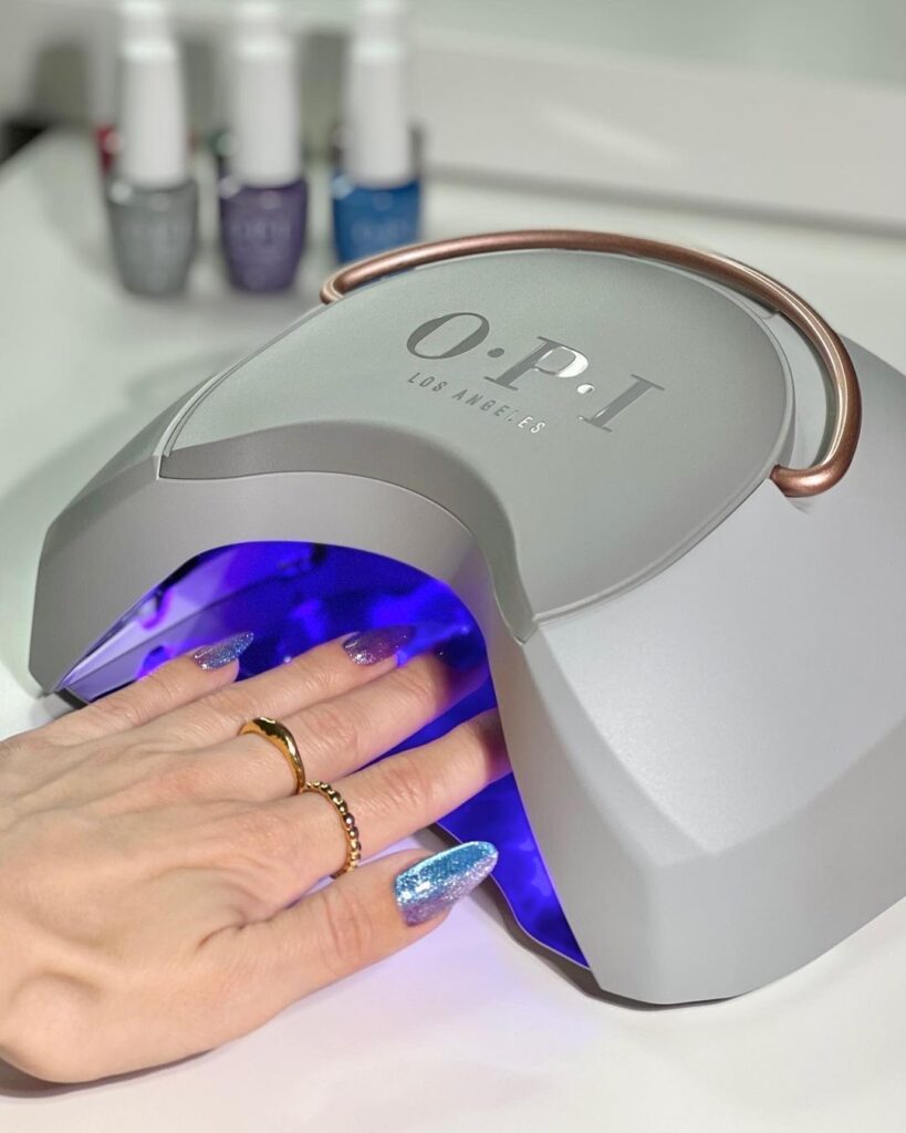 A faceless woman hand, curing her nails under an OPI LED nail lamp