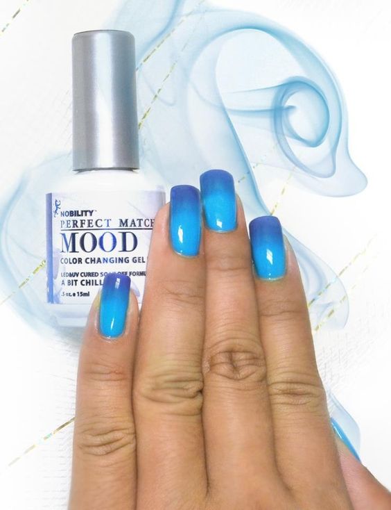 A faceless woman is depicted wearing Perfect Match Mood Color Changing gel polish in a light blue shade, with a bottle of the color-changing gel polish nearby in the same hue.