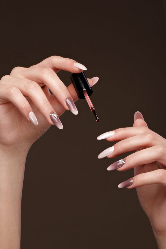 Beautiful classic manicure on female hand with oil for cuticles. Close-up. Picture taken in the studio. Ombre nails. painted nails. nail polish