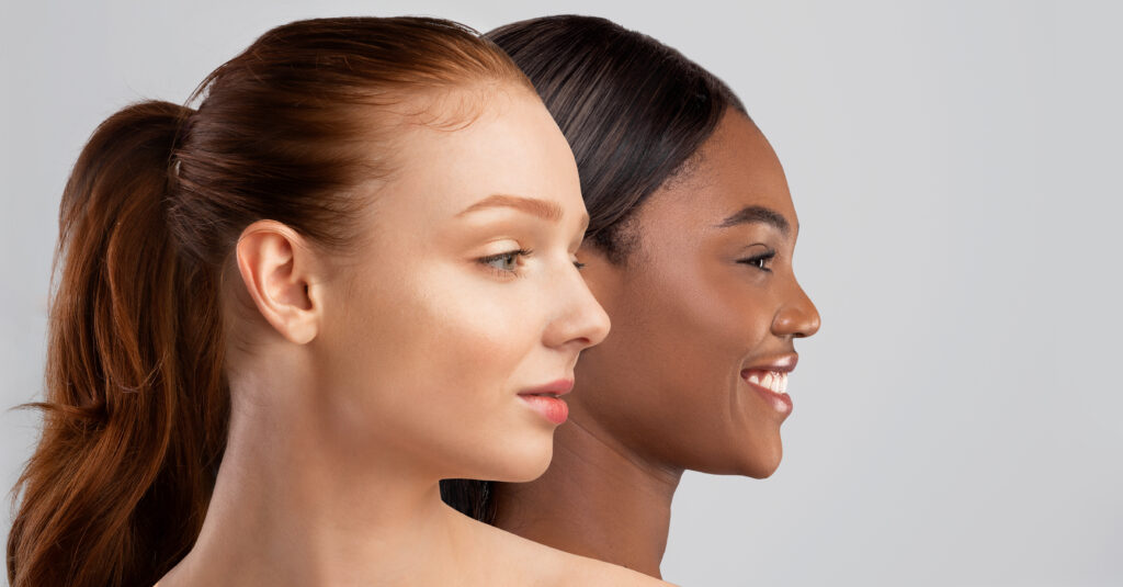 Face highlighters Finishes and shades. Diversity in beauty. Sensual smiling dark-skinned and pale red-haired half-naked females young women posing on grey studio background, looking at copy space, closeup, banner, collage