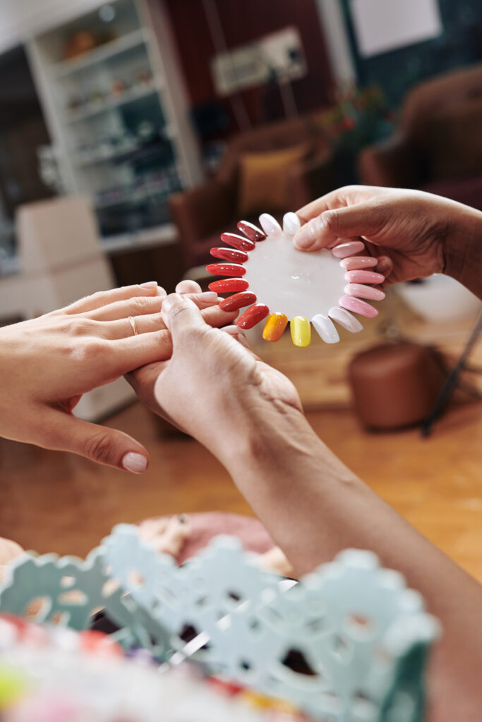 Close-up image of manicurist using round nail polish palette when helping client to find perfect color and nail shape. 