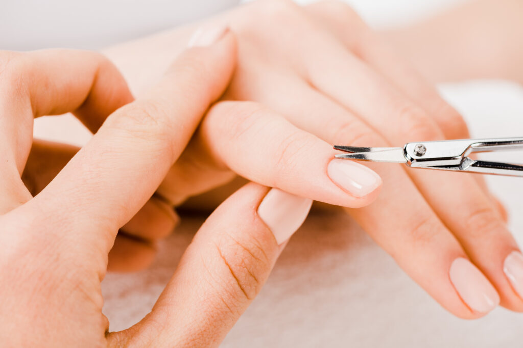 Cropped view of manicurist using manicure scissors to remove cuticle. cuticle scissors