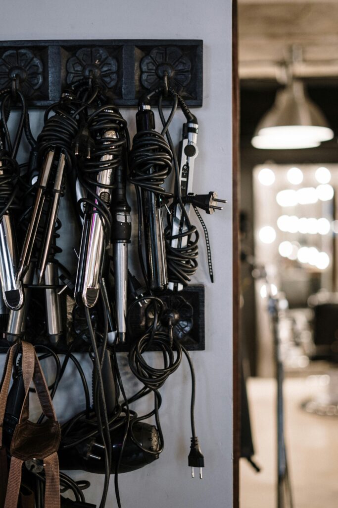 Different shapes, types, and sizes of curling irons displayed on a wall.