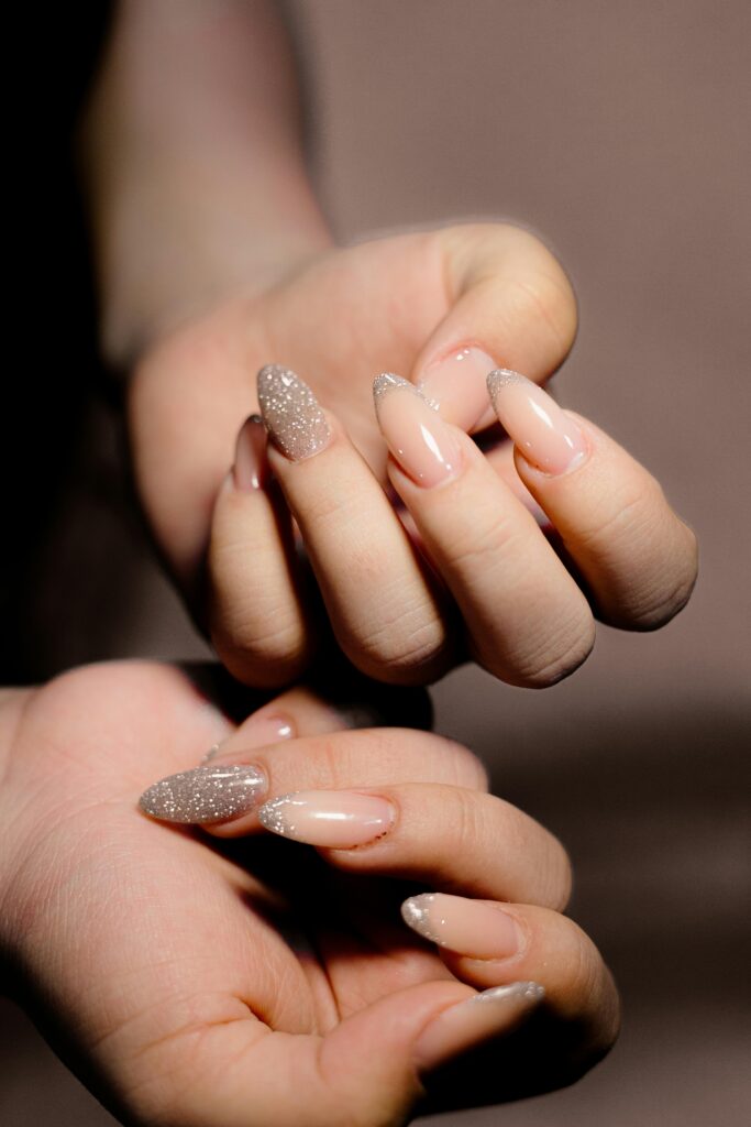 A close-up of a hand featuring trendy summer nail designs. French glittery summer nails. Summer nail polish shades