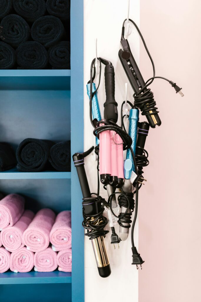 Various colorful curling iron products displayed in a home bathroom, showcasing different types, sizes, and shapes.