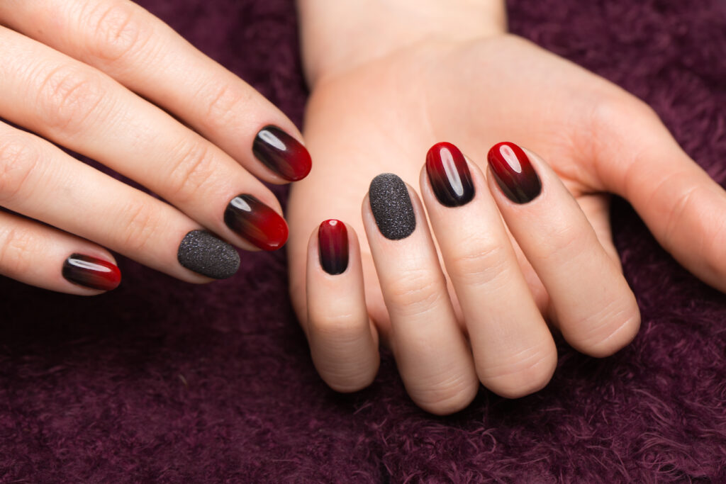 A faceless woman is shown wearing Perfect Match Mood Color Changing gel polish in a red and black shades.