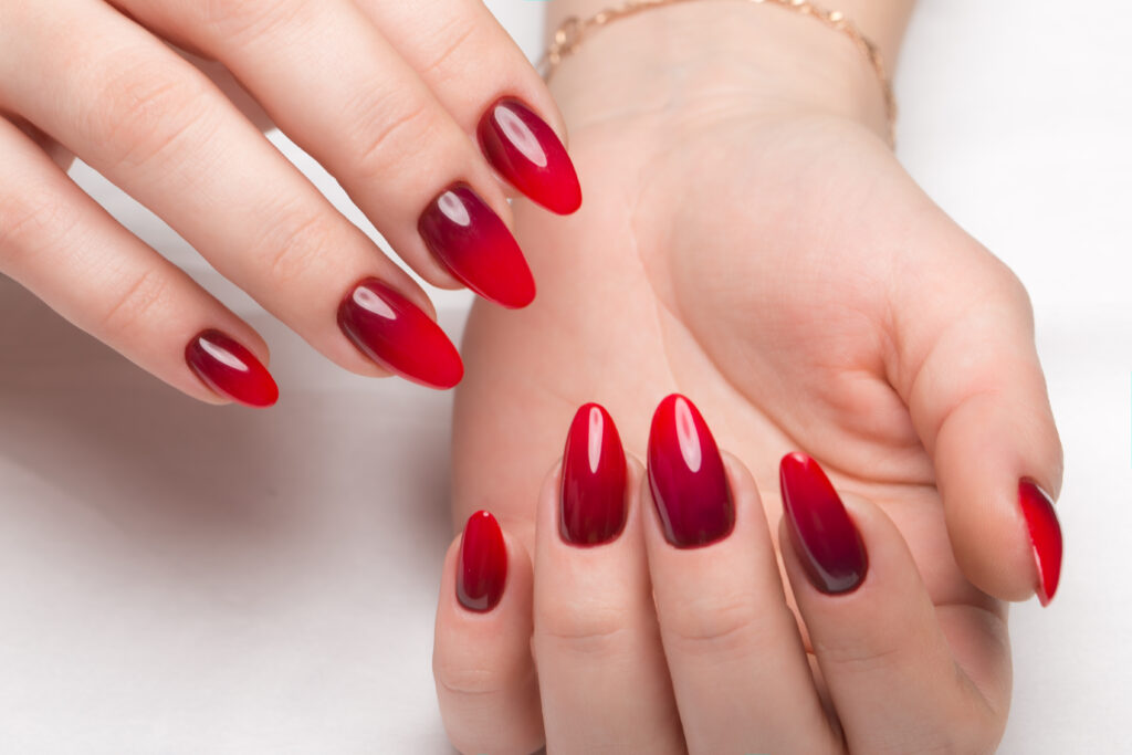 A faceless woman is shown wearing Perfect Match Mood Color Changing gel polish in a red shade, with long nails.