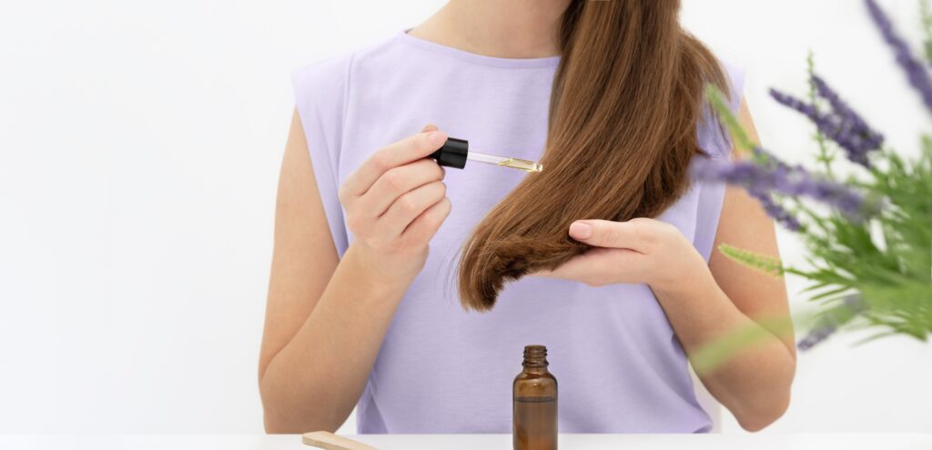 Woman applying hair serum on her hair.