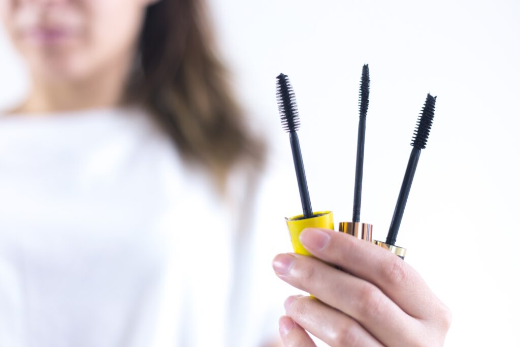 A lady holding different shapes and sizes of mascara brush