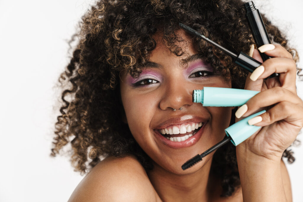 Beautiful joyful african american girl posing with mascara isolated over white background