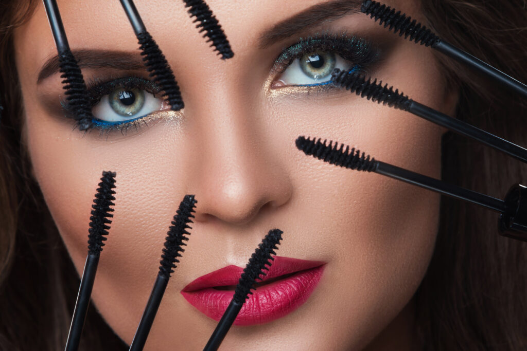 Beautiful woman with beautiful make-up applying mascara on her lashes