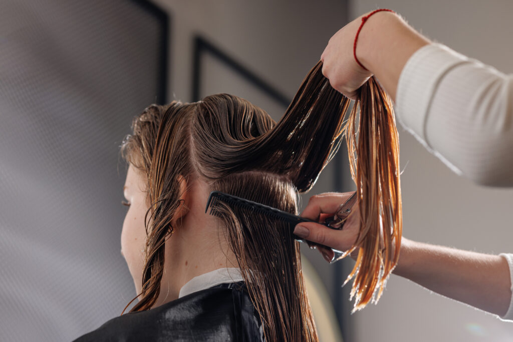 beauty master combing wet hair of a client in a beauty salon close-up. hair perm