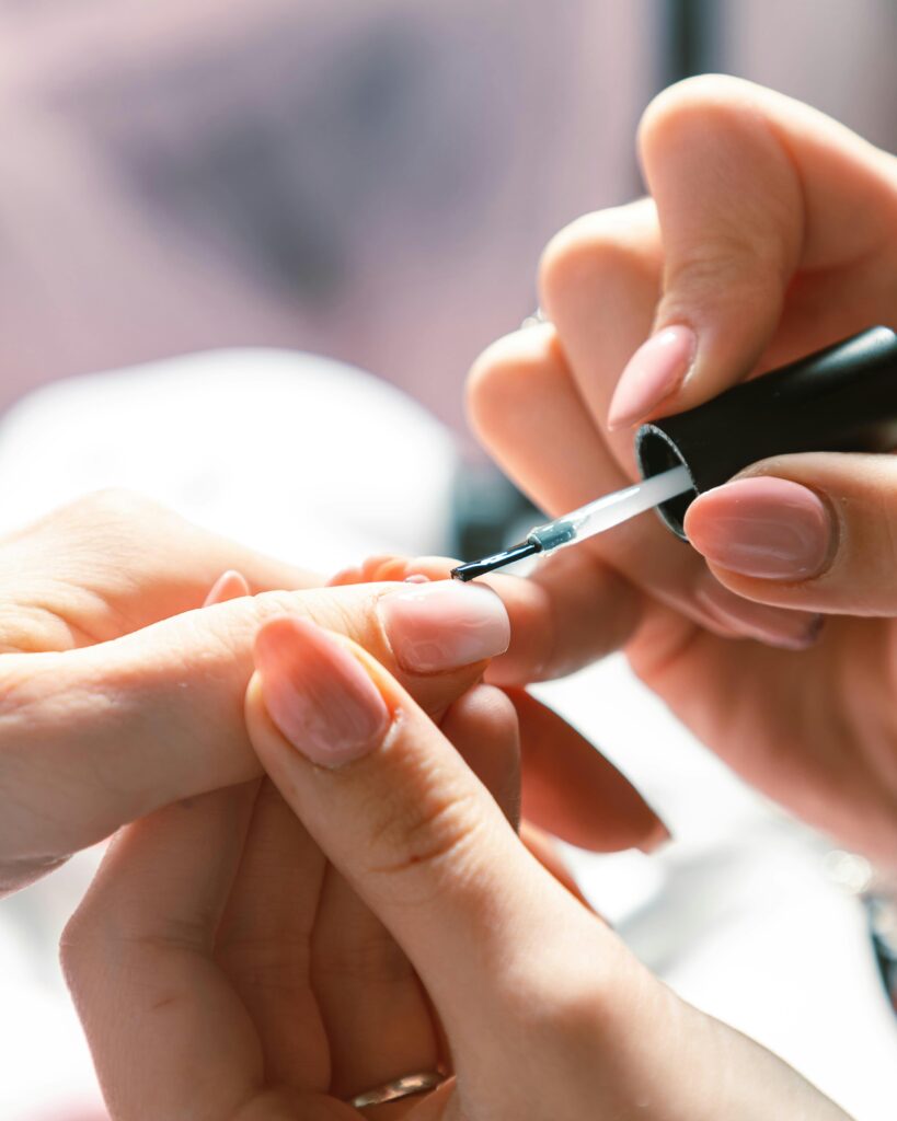 A faceless woman taking care of her nails, applying base coat on her nails. preparing nails. nail care