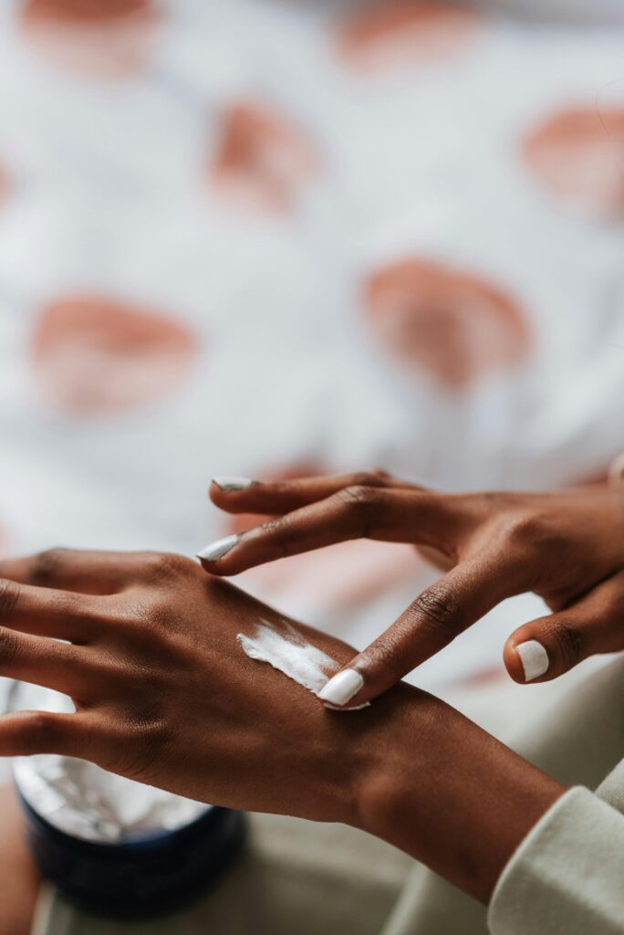 A faceless woman taking her of her nails and applying hand cream