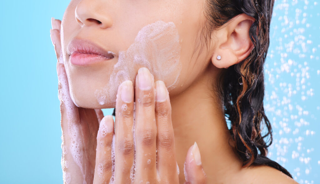 Studio shot of an unrecognizable young woman showering against a blue background. face wash. face care