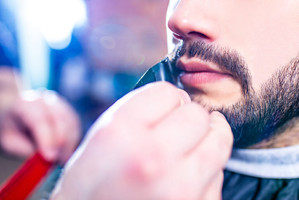 arabic handsome bearded man getting haircut at barbershop.. hair trimmers