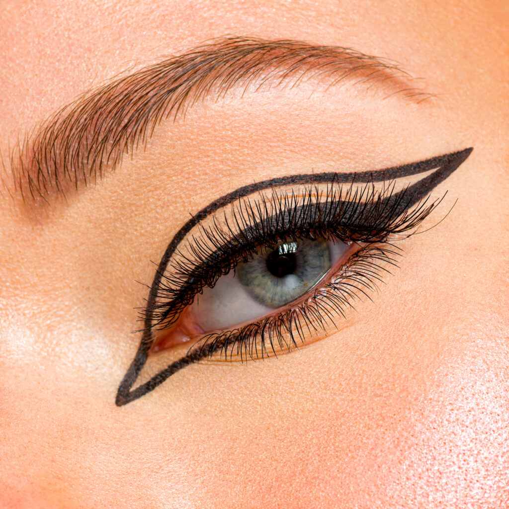 Beautiful girl with makeup in the form of arrows. Face of a young girl close-up with fashionable makeup over beige background. Stylish makeup. eyeliner