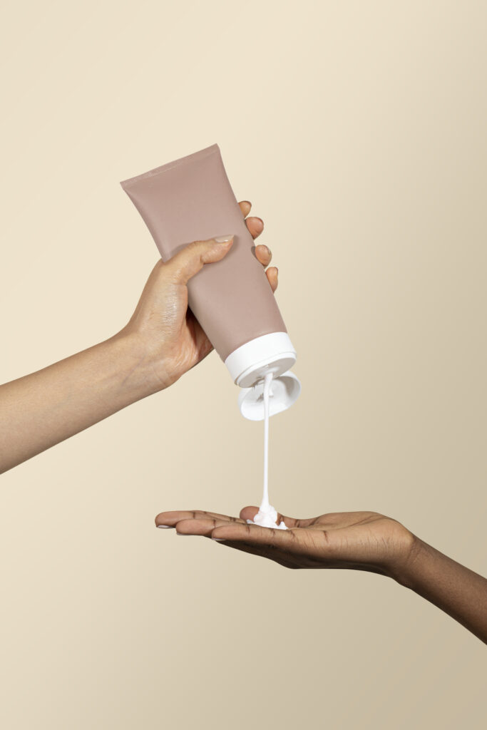 Woman squeezing cream from an unlabeled beige tubeز 