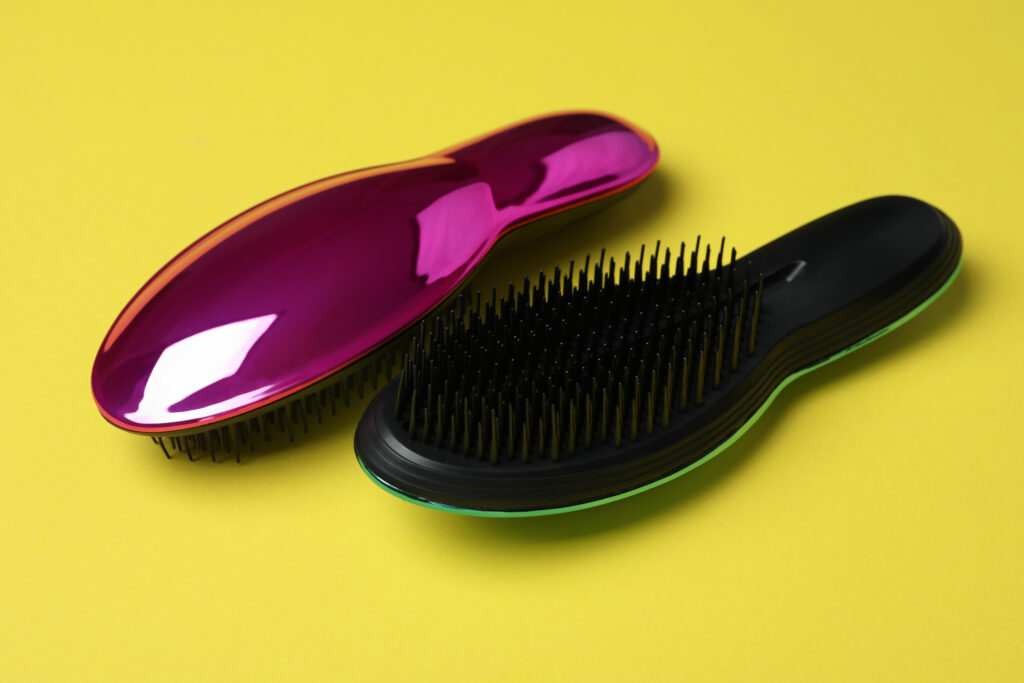 Detangling Brushes. Colored plastic hair brushes on yellow background