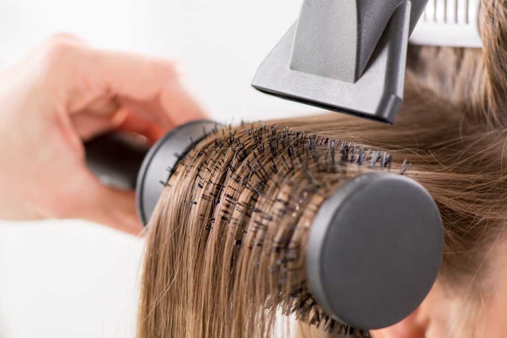 Round Brushes. Drying long brown hair with hair dryer and round brush. Close-up.