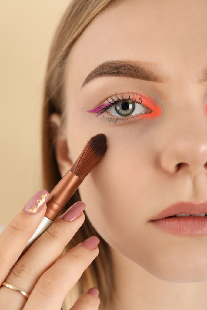 Model face with makeup on beige background, close up