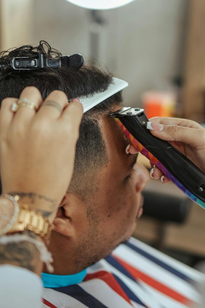 A hair stylist is using a hair trimmer to style a client's front hair.
