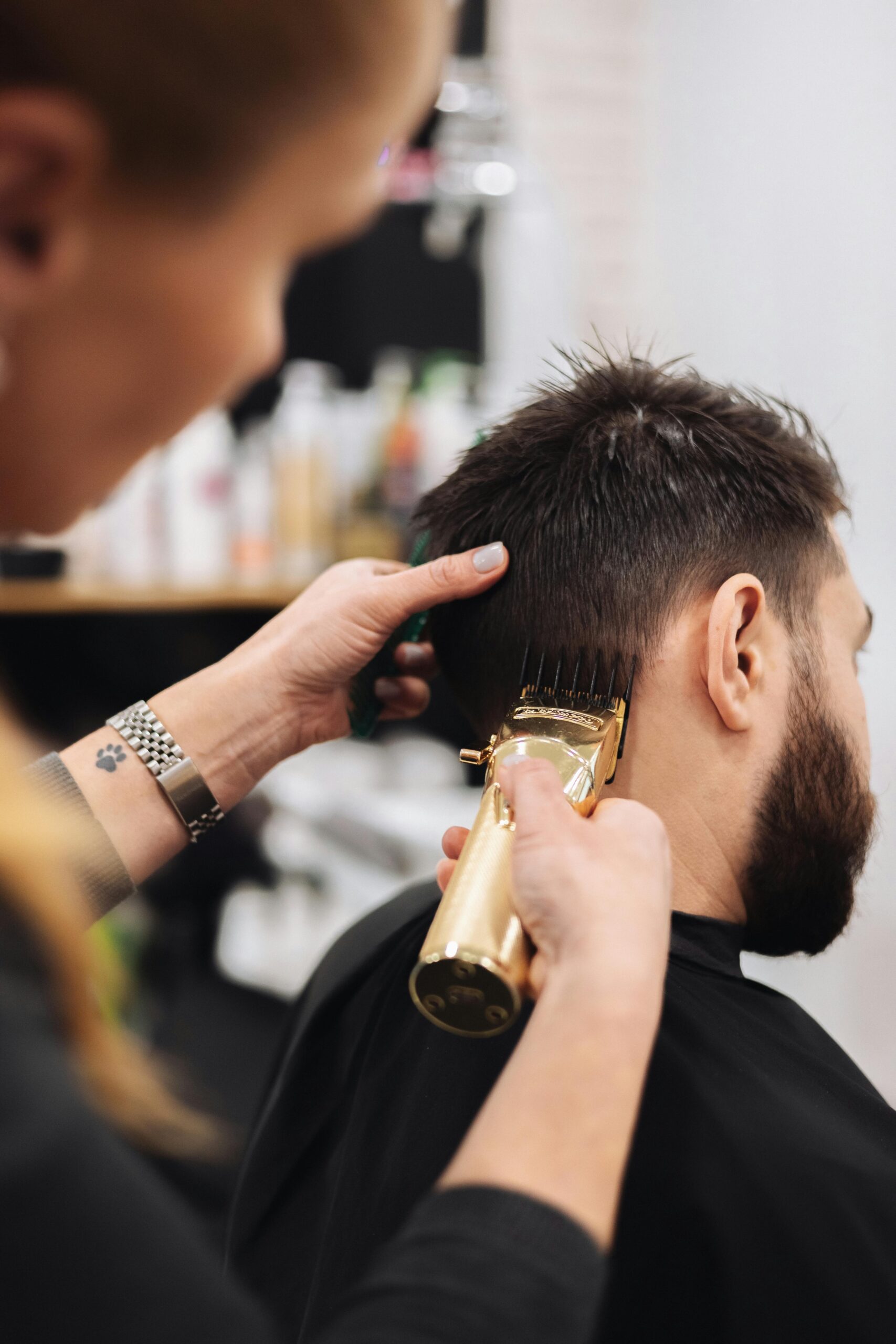 A professional stylist is using hair trimmers to cut a client's hair.