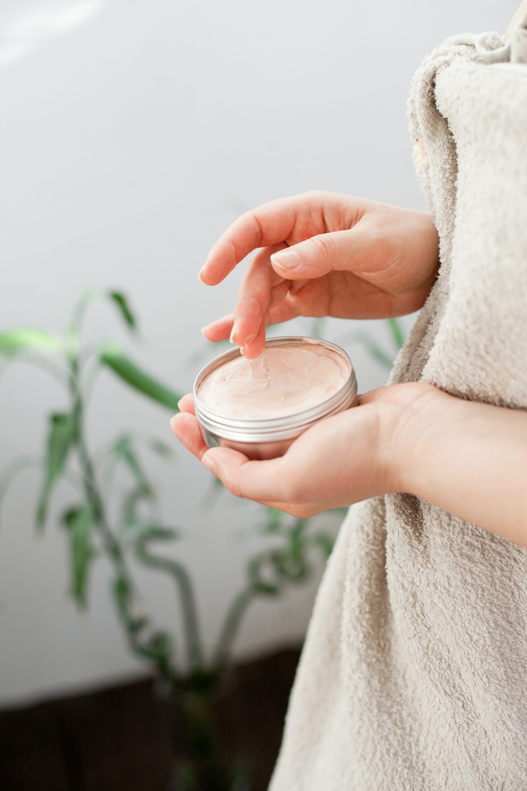 A faceless woman applying body butter with hands to moisturize her skin