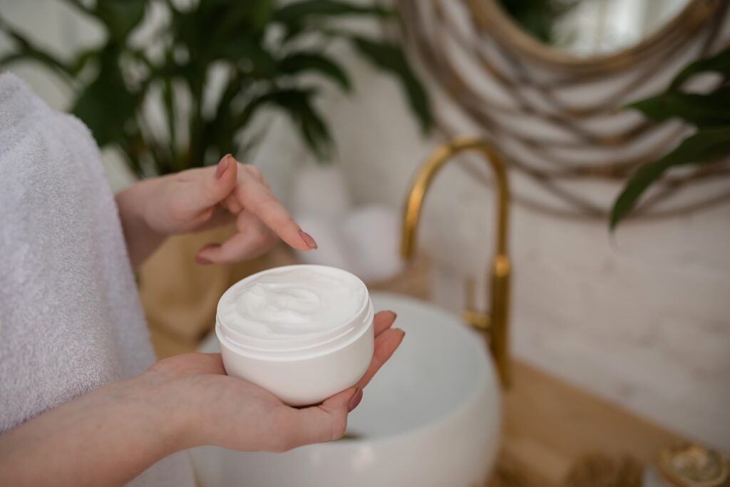 A faceless woman applying cream to moisturize her body.