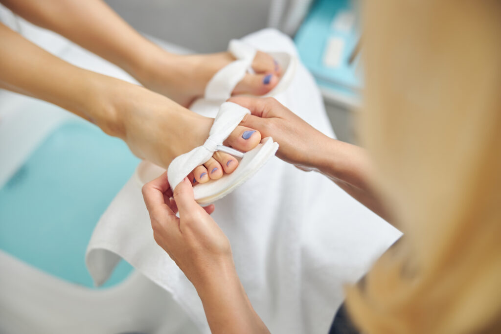 Top view close up of lady taking care of female feet after pedicure in spa salon