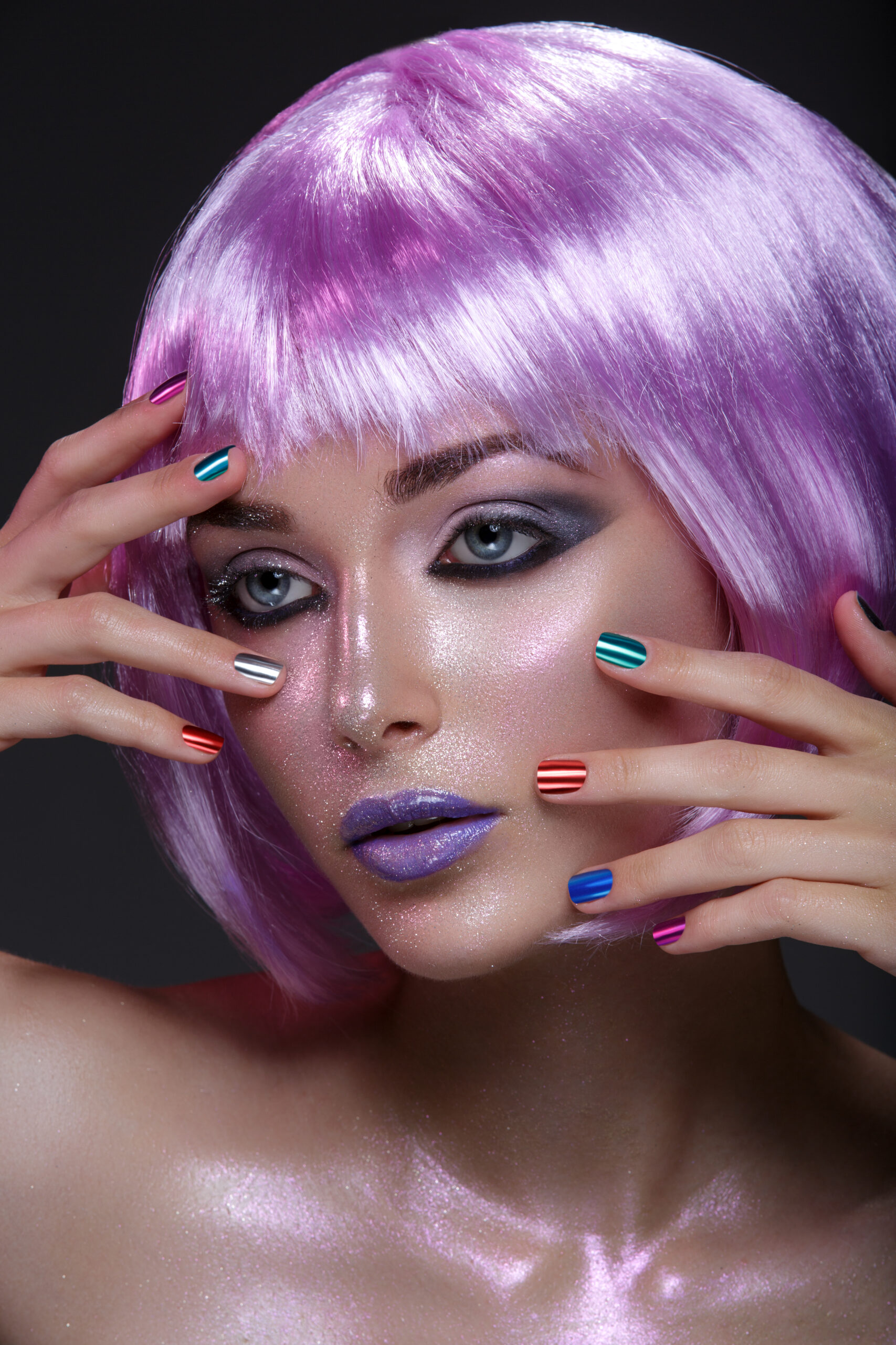 Beautiful young woman in purple wig with artistic violet lipstick and eye makeup with pink sparkles. Beauty shot on black background. Colorful nails. nail effects. woman earing colorful nail effects. woman wearing makeup.