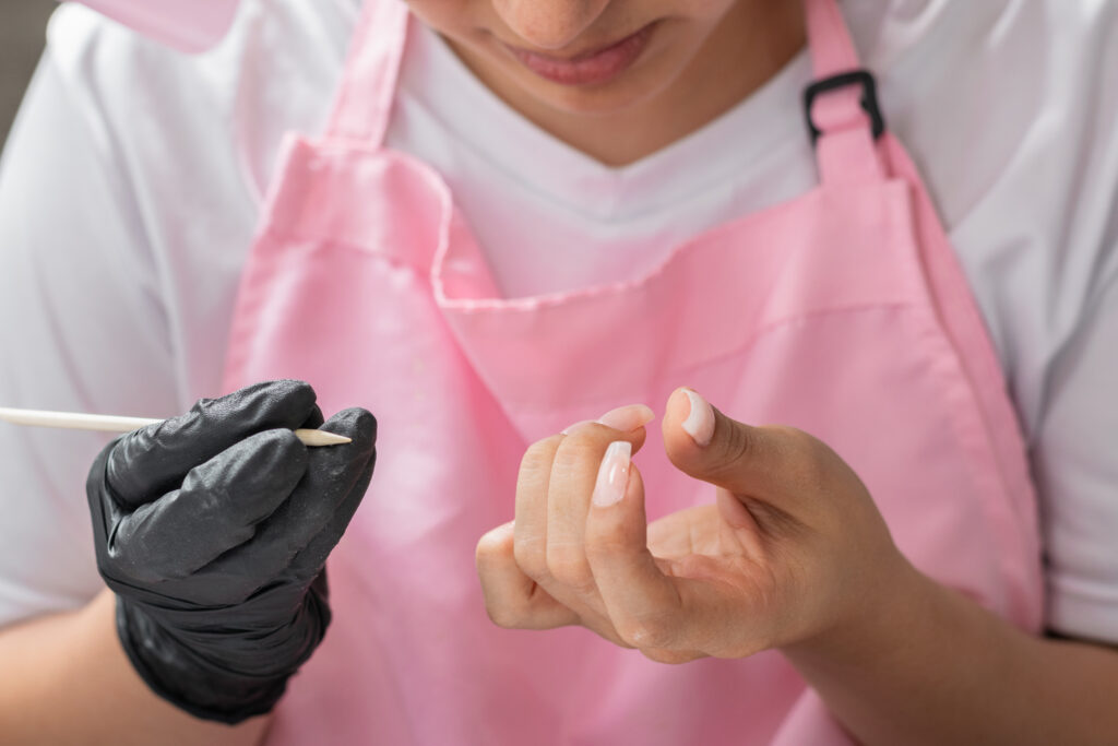 close-up of the hands of a woman cleaning her fingernails with a wooden stick.