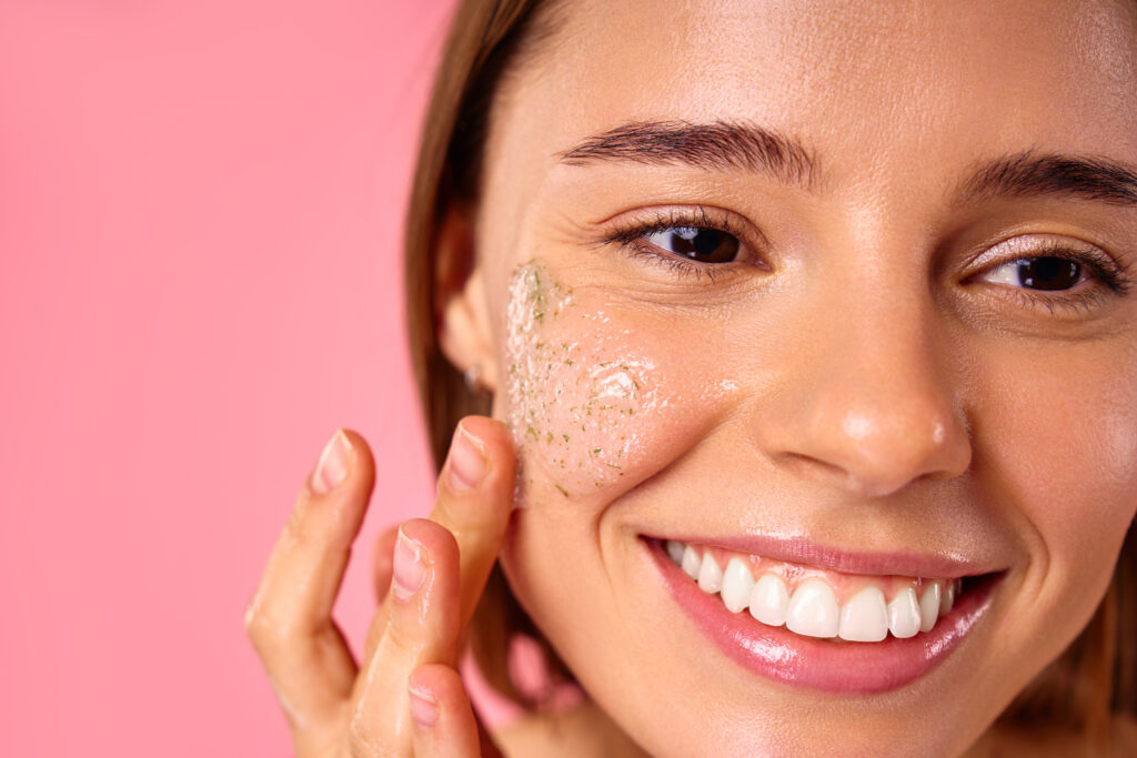 Beautiful happy woman using moisturizing face mask isolated on pink background. Skin care, cosmetology, beauty concept. face care. Skin care.