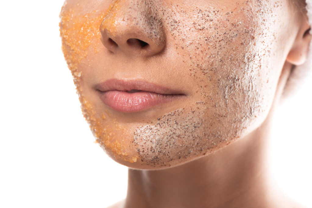 cropped view of young woman with scrub on face isolated on white.