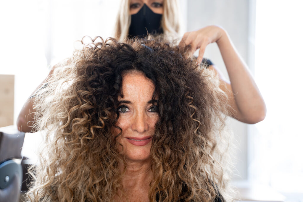 Frontal view of a hairdressing arranging the hair of a client in a salon.