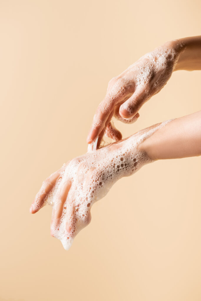 partial view of female hands in soap foam isolated on beige.