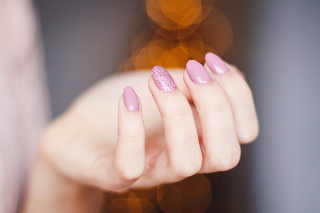 A faceless woman hand. her ails are painted in a beautiful nail polish shade with glittery nail effects.