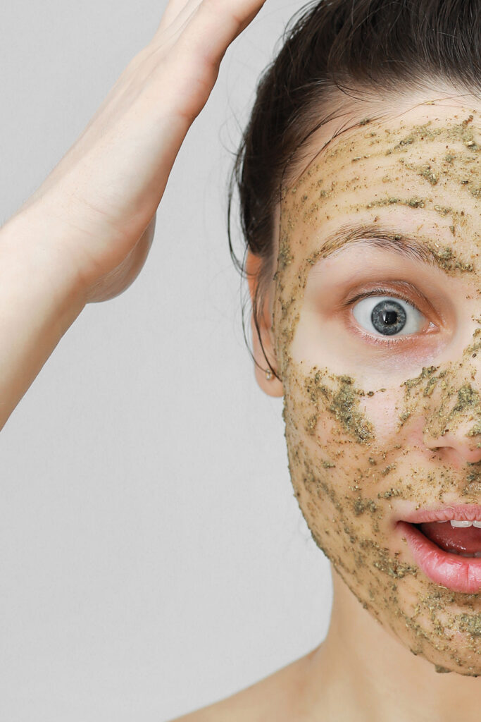 Facial Scrub Potential Risks and Precautions. Skin Care. Cosmetic Day. young girl in home style, her hair gathered with her hands at the top. With eco, herbal, natural mask, green on the face