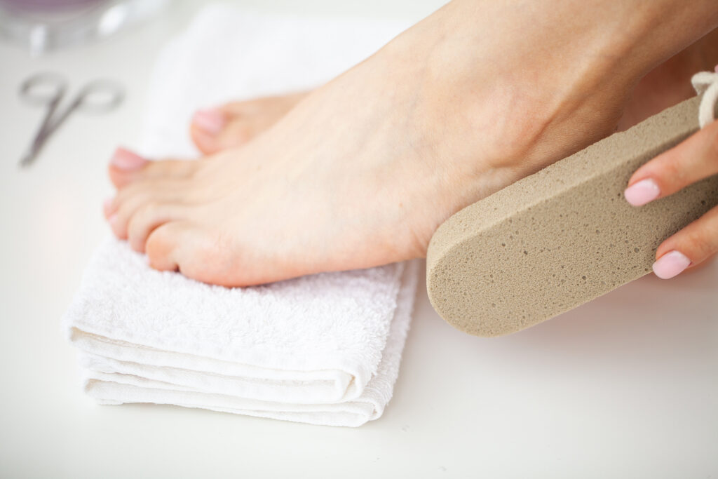 Woman cleans the heel of the foot with pumice. Feel file. Heel file.