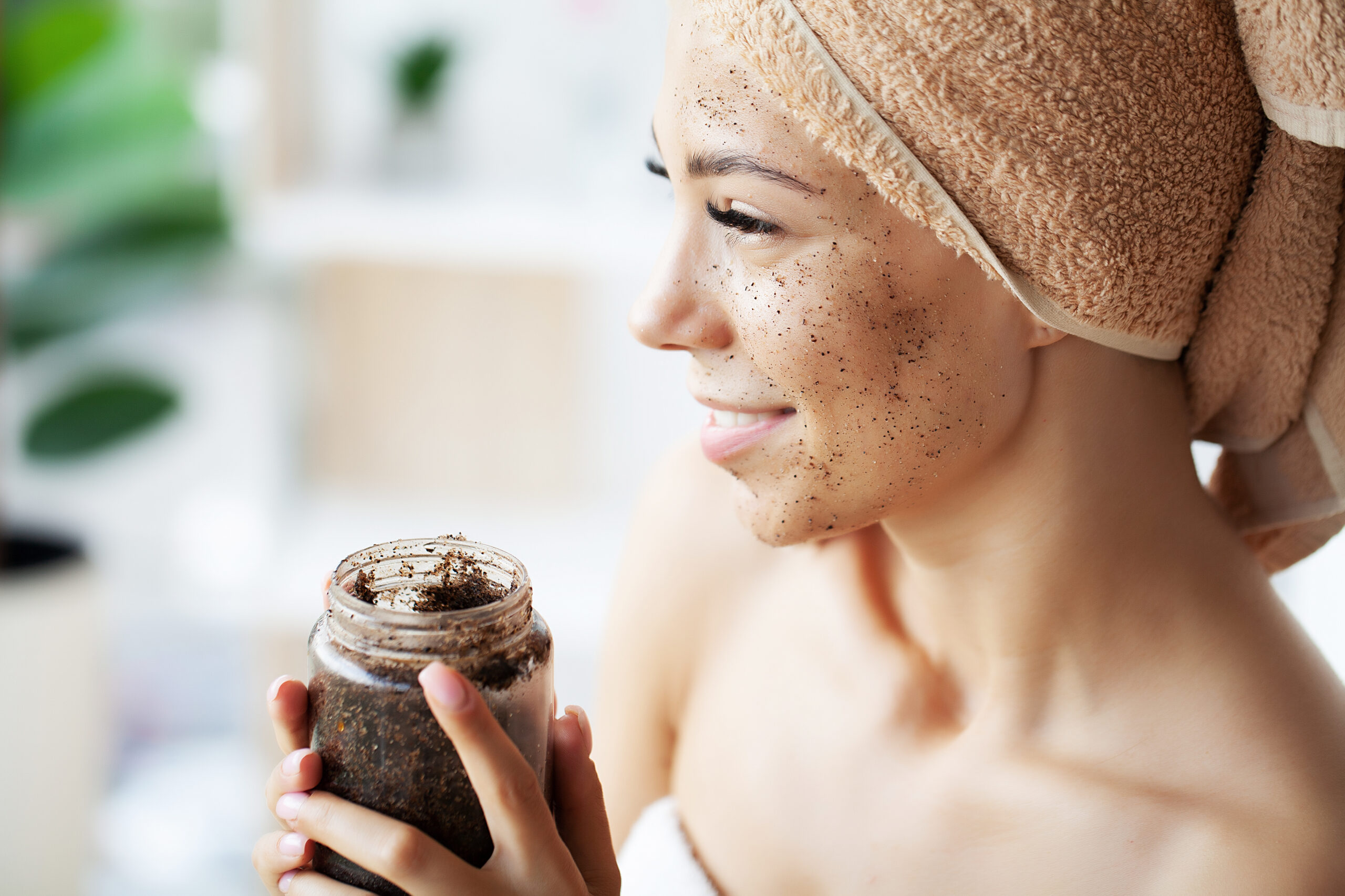 Young woman applying scrub on face in bathroom. Facial scrub. face care. skin care