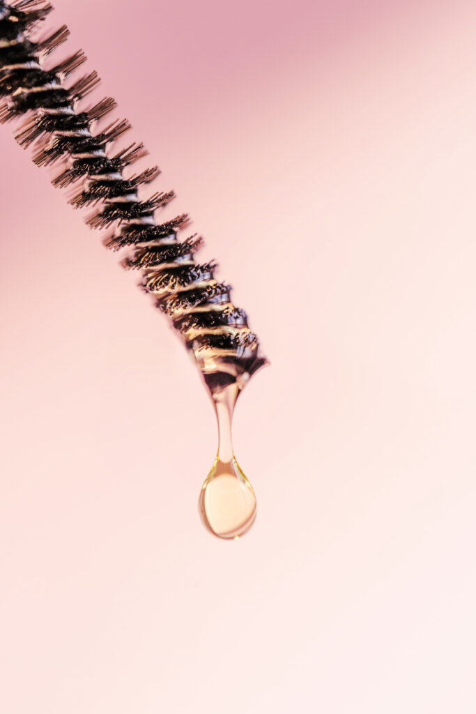 A drop of oil for eyebrows and eyelashes falls from the brush on a pink background . Perfect for showcasing your product. Front view. Choosing the Right Lash Serum for You.