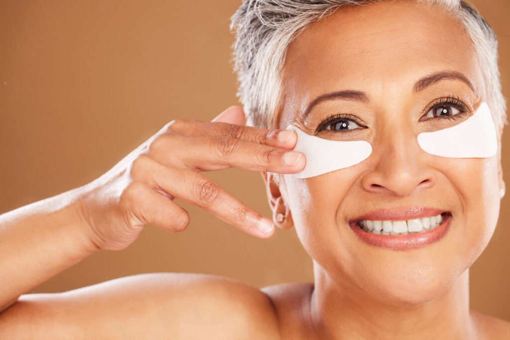 Beauty, skincare and senior woman with eyepads on face for a natural facial routine in studio. protect eye area from the signs of aging