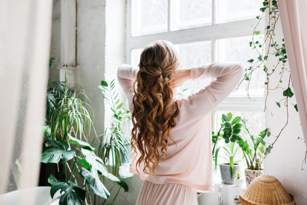 blonde girl with long hair looks out the window. everyday hair styling. 