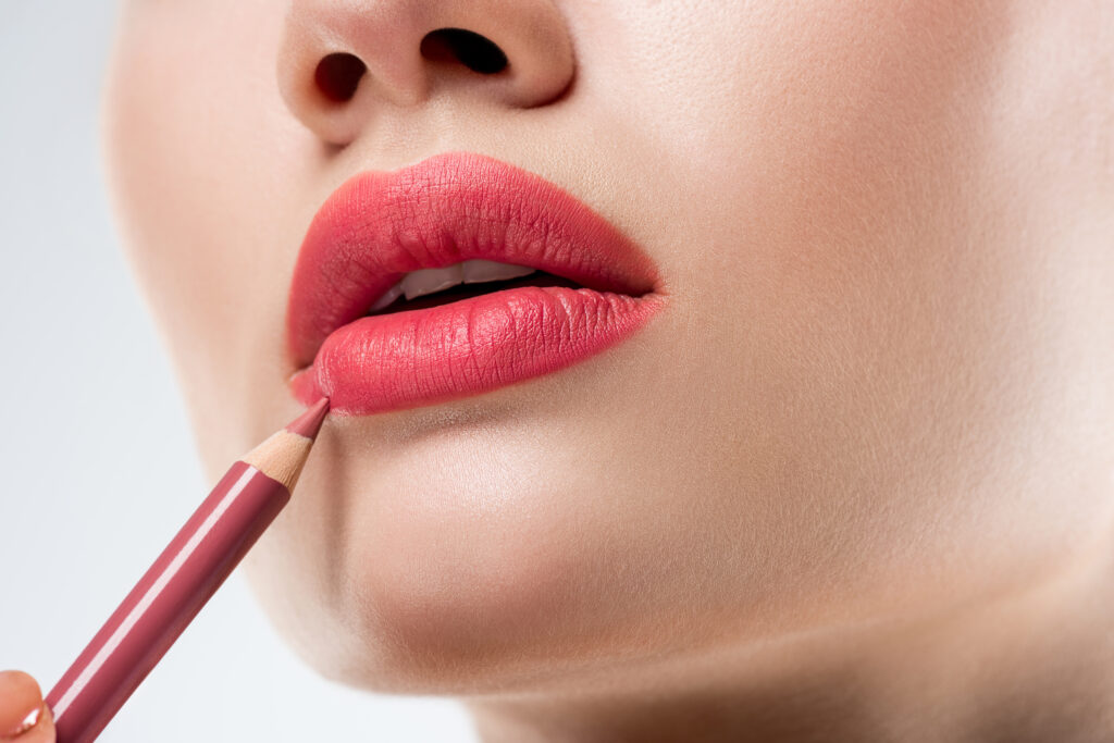 close up studio shot of woman applying lip pencil,  isolated on white. Lip liner.