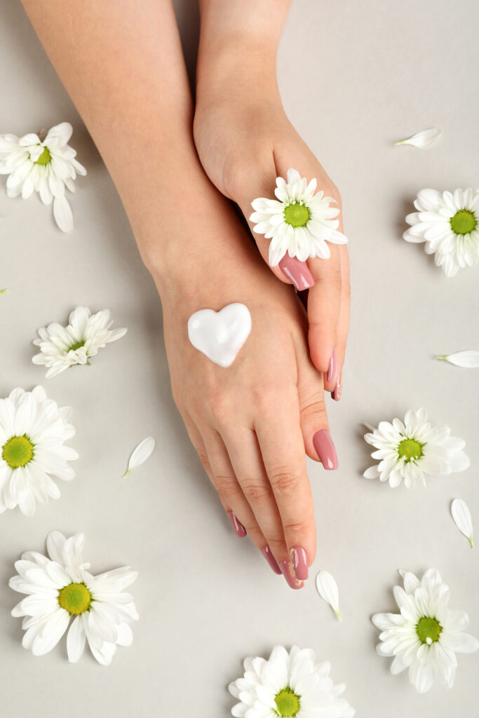 Concept of hand care on gray background with flowers.