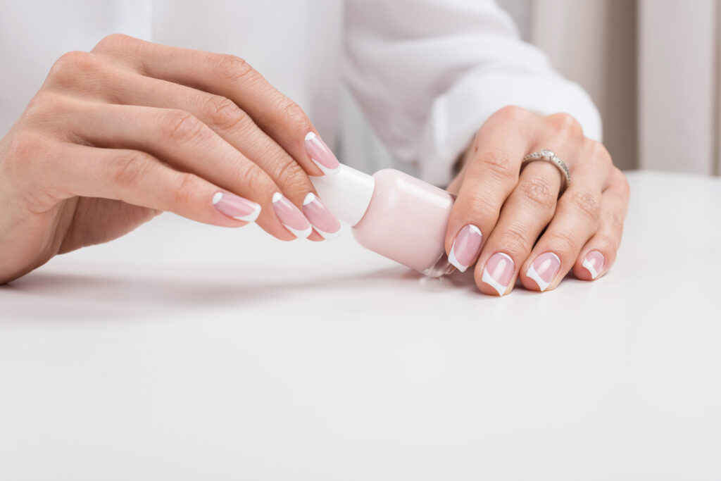 cropped shot of woman holding nail polish while doing manicure