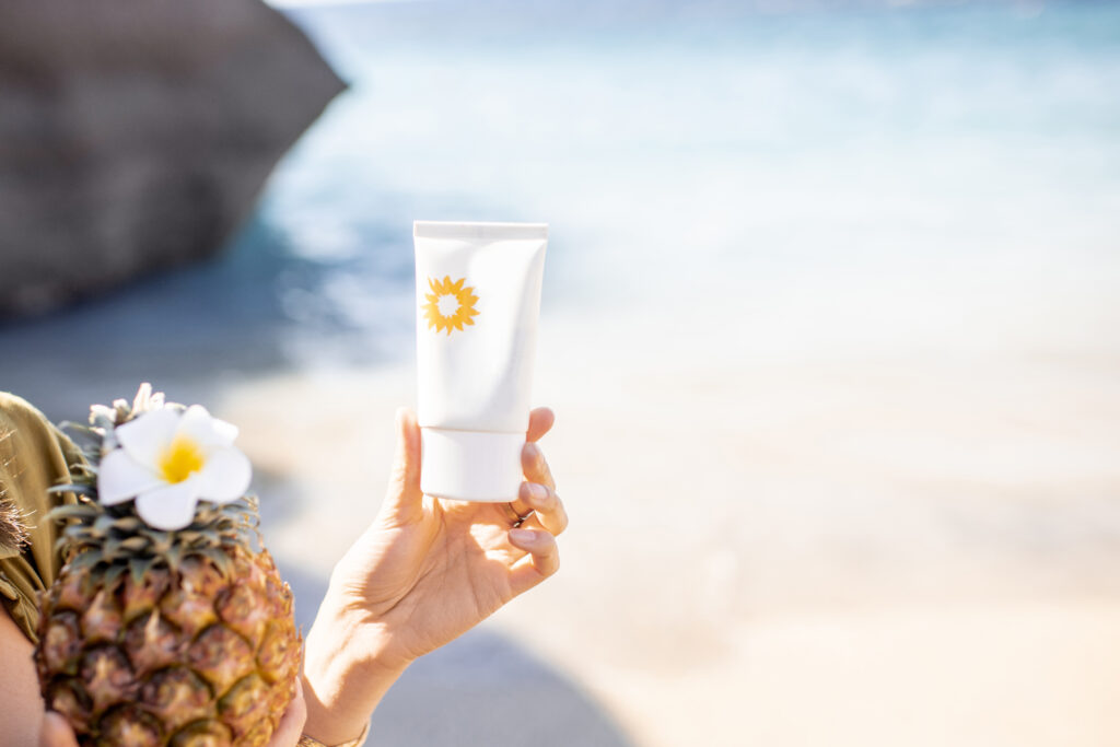 Woman holding sunscreen lotion on the beach, close-up on the tube