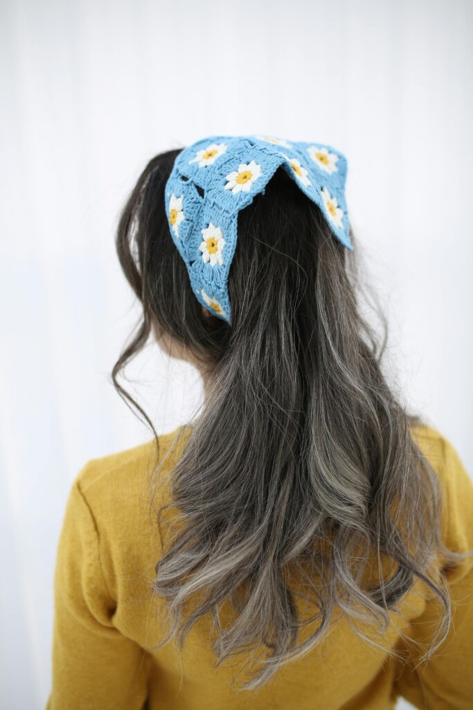 a girl with dark to grey ombre hair wears a blue headband adorned with yellow and white daisy patterns. The headband adds a vibrant touch to the monochromatic hair. Everyday Hair Styling